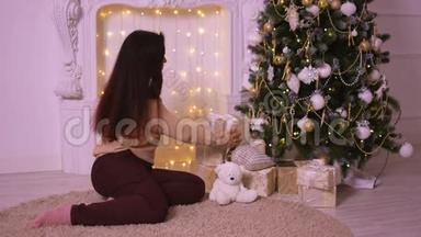 圣诞节壁炉旁美丽的年轻女子把礼物放在树下送给她的爱人。